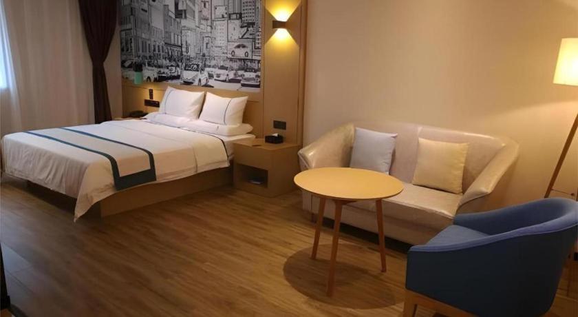 ein Schlafzimmer mit einem Bett, einer Couch und einem Tisch in der Unterkunft City Comfort Inn Mianyang Southwest University Of Science And Technology in Qinglianchang