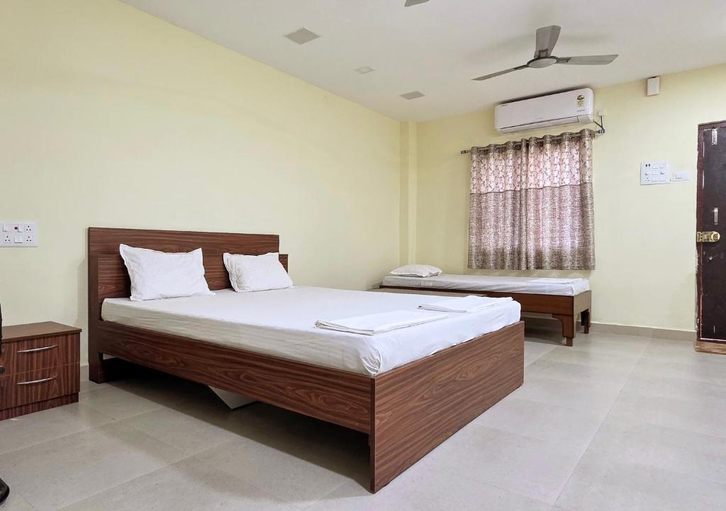 Un dormitorio con dos camas y una ventana. en Aathidya Lodge, en Ādoni