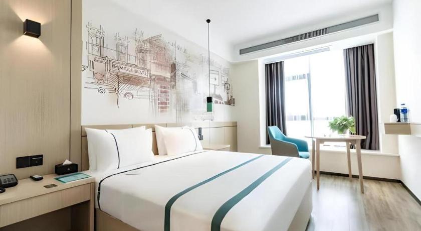 une chambre d'hôtel avec un grand lit et un bureau dans l'établissement City Comfort Inn Hefei Mingzhu Square Fanhua Avenue, à Hefei