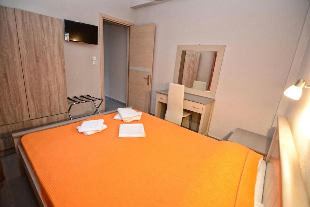 an orange bed in a room with a table at Melissa Rooms in Agios Kirykos