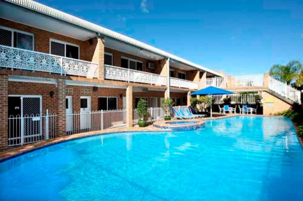 a large swimming pool in front of a building at The Hermitage Motel - Campbelltown in Campbelltown