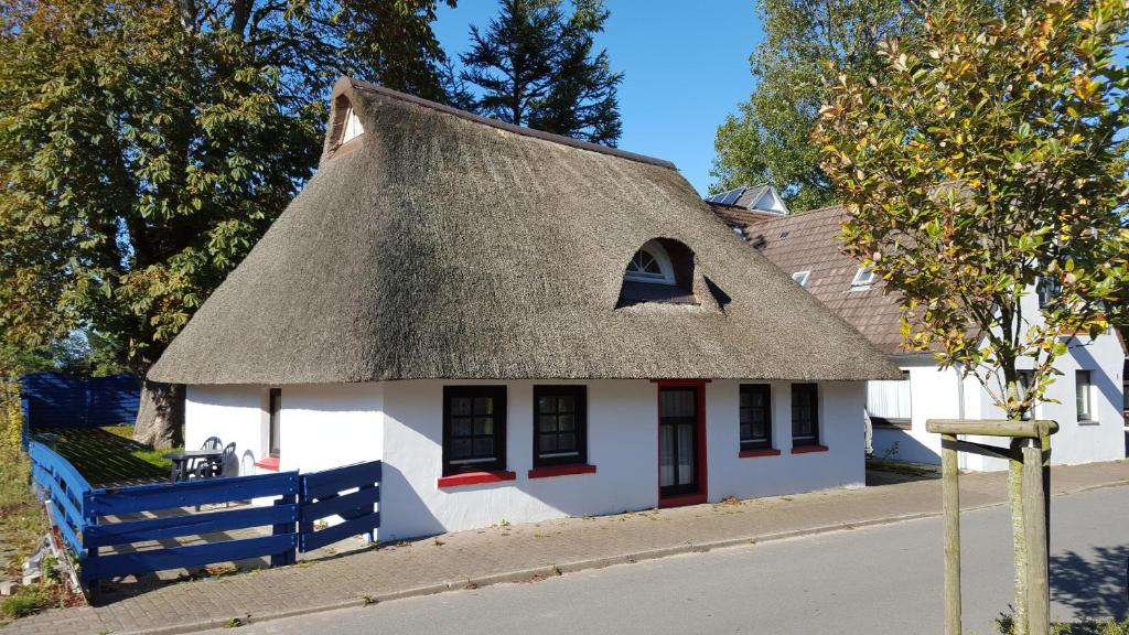 una pequeña casa blanca con techo de paja en Holiday Homes Buchholz, en Büsum