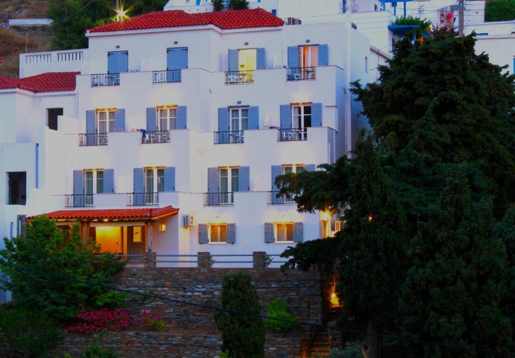 un grand bâtiment blanc avec un arbre en face dans l'établissement Villa Nefeli, à Batsi