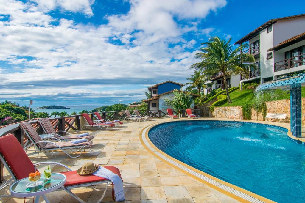 uma piscina num resort com cadeiras e uma mesa em Hotel Ilha Branca Inn em Búzios