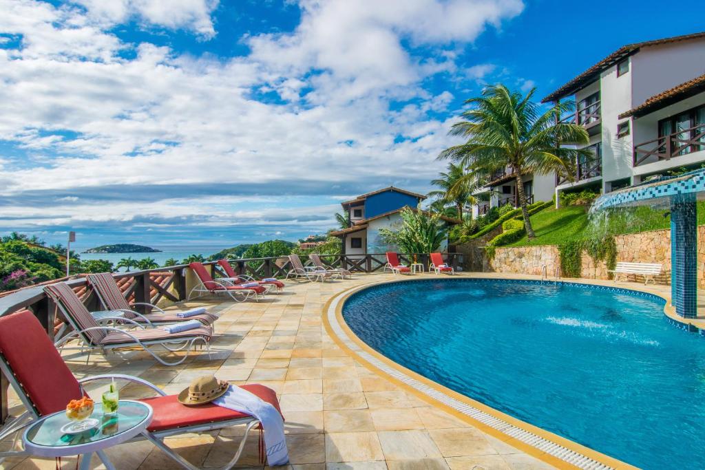 a pool at a resort with chairs and a table at Hotel Ilha Branca Inn in Búzios