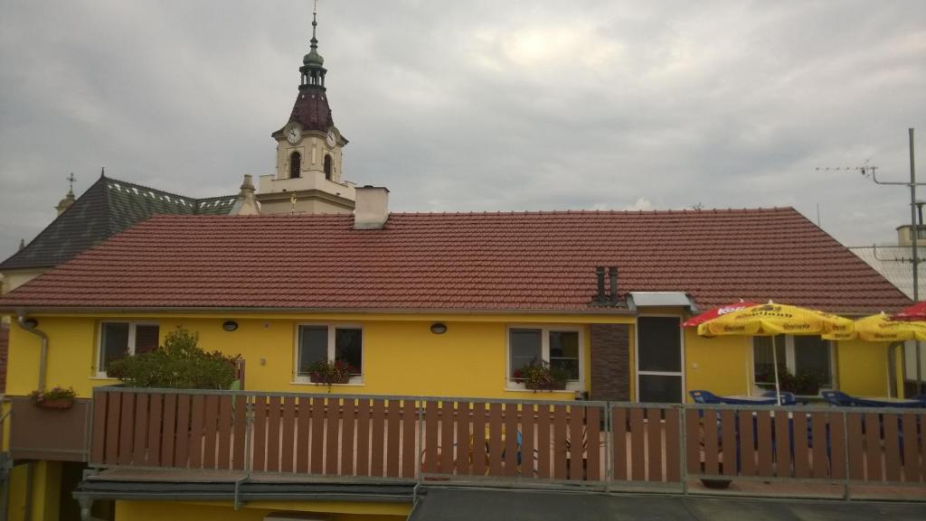 ein gelbes Haus mit einem Uhrturm darüber in der Unterkunft Penzion Toscana in Lanžhot