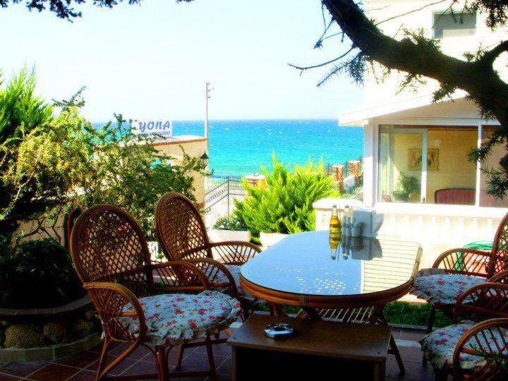 a patio with a table and chairs and the ocean at Yona Motel in Çeşme