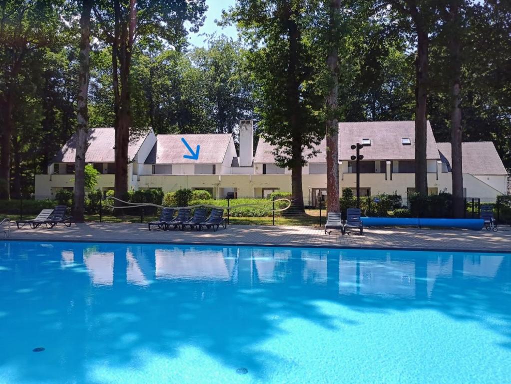 a large swimming pool with a house in the background at Studio Eik 105 at the pool in nature domain in Aan de Wolfsberg