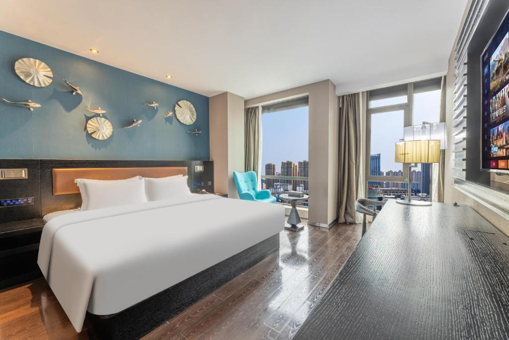 una camera da letto con un grande letto bianco e una grande finestra di Guangzhou Baiyun Airport Orange Crystal Hotel a Huadu