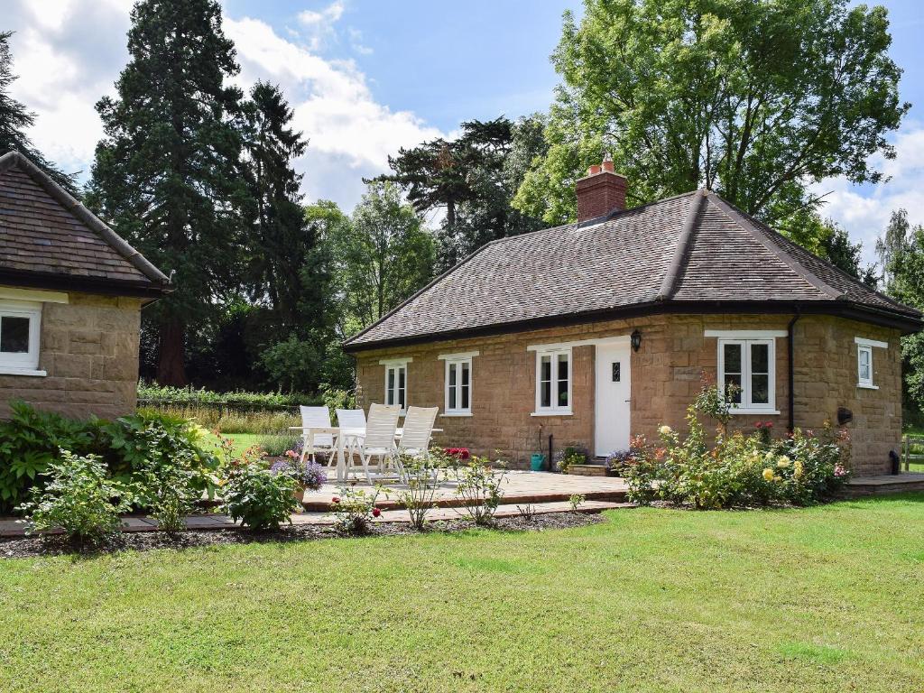 a brick house with white chairs in a yard at Wishing Well Cottage in Mathon