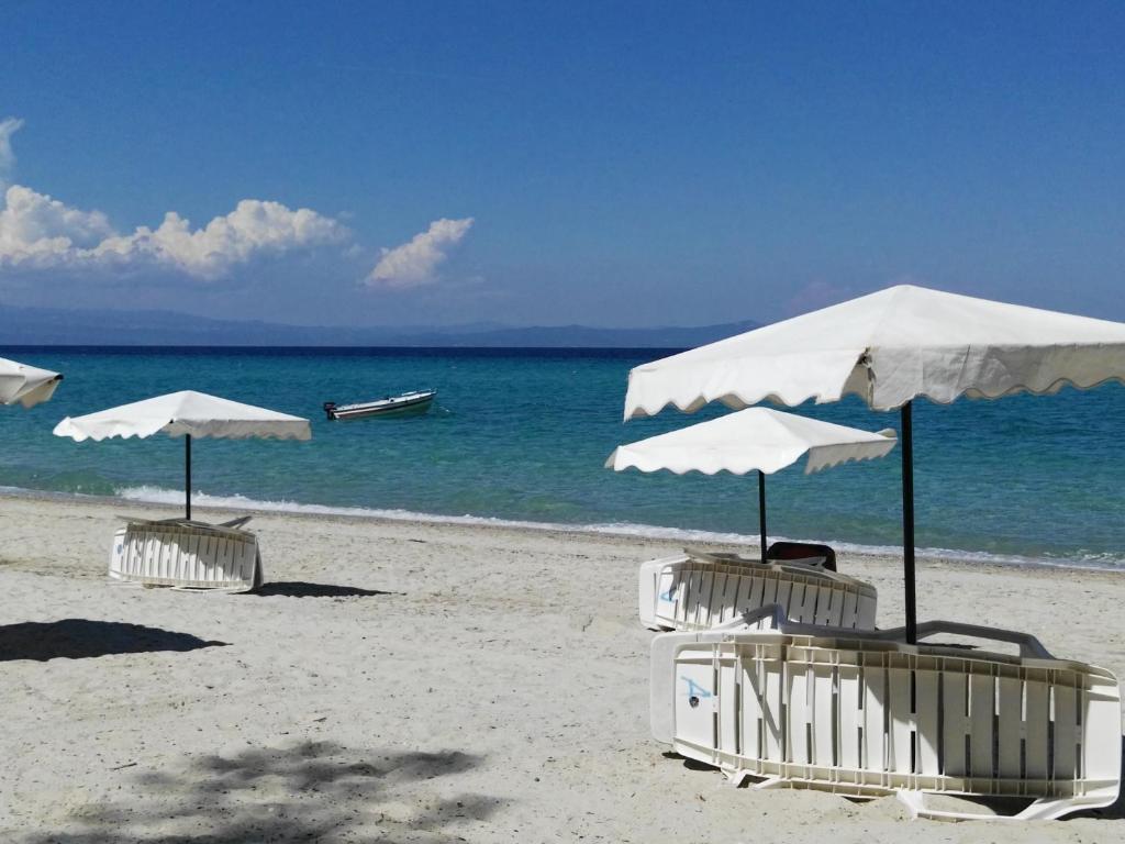 two umbrellas and chairs on a beach with the ocean at Ariadni -Villas- luxury houses in Kriopigi
