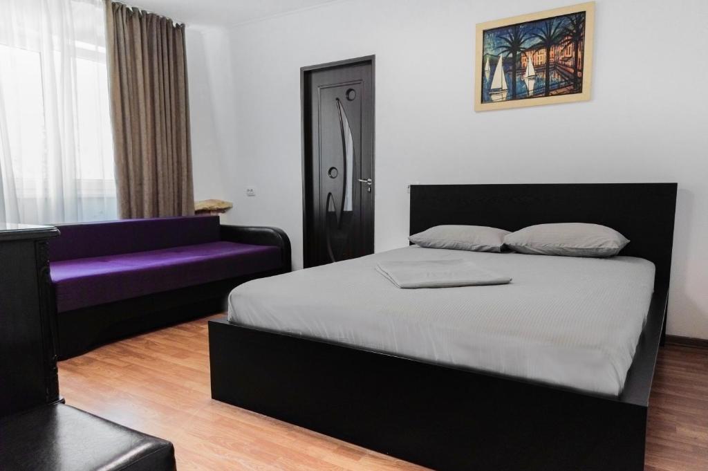 a bedroom with a bed and a purple couch at Garsoniera in Mangalia