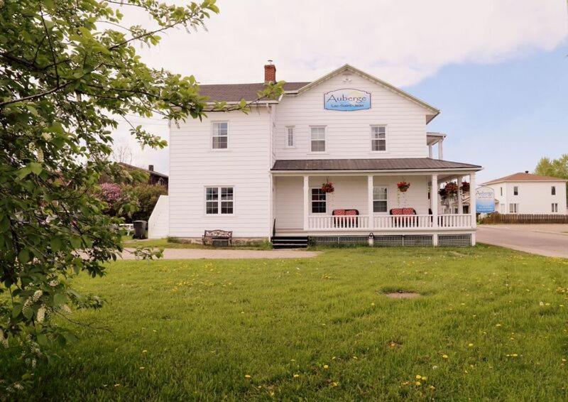 une maison blanche avec un panneau sur son côté dans l'établissement Auberge Lac-Saint-Jean, à Roberval