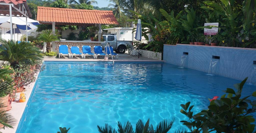 una gran piscina con sillas azules en un patio en Hotel Maricarmen, en Manzanillo