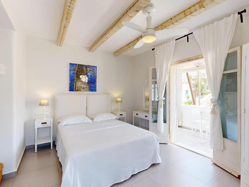 Una habitación blanca con una cama y una ventana en Speires suites, en Iraklia