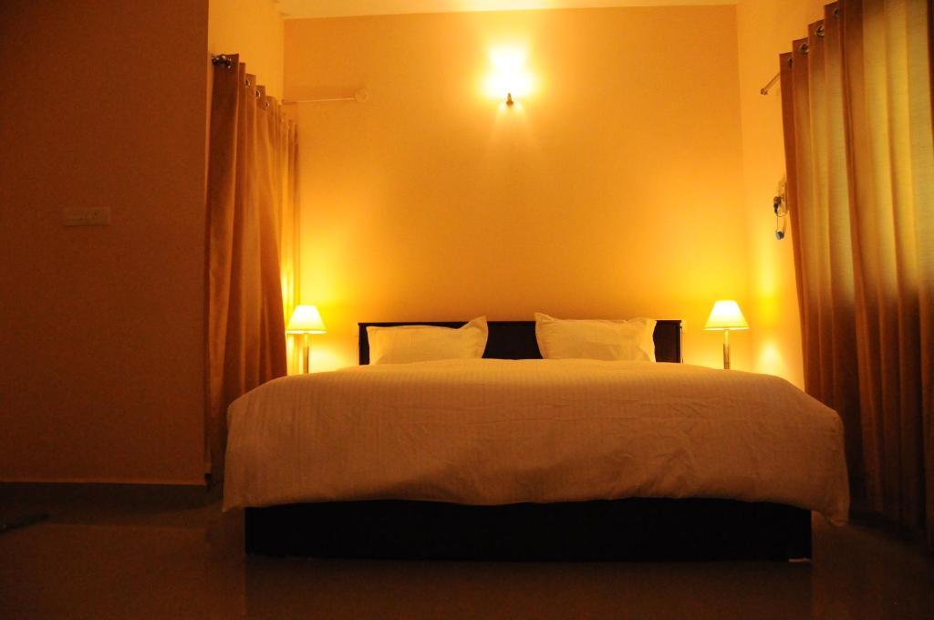 a bedroom with a large bed with two lamps at Jyothi Suites in Srīrangam