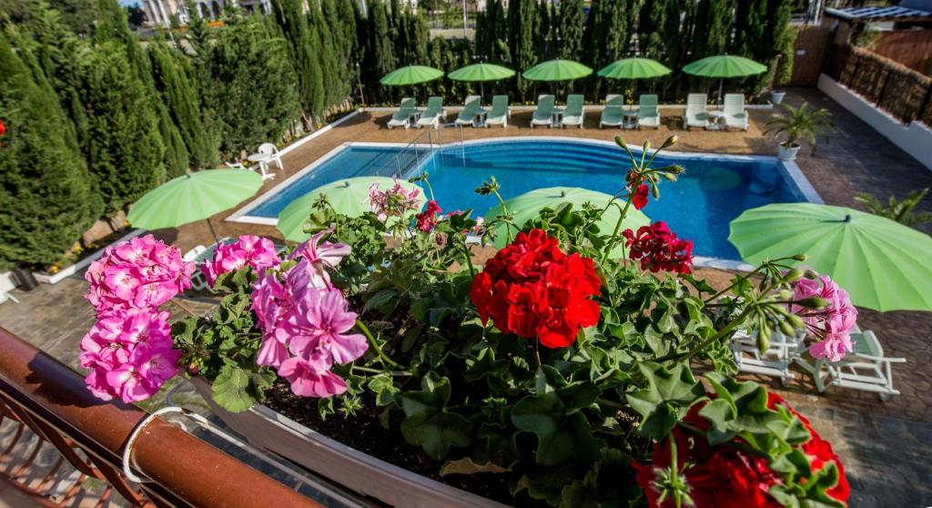 a swimming pool with some flowers and umbrellas at Belle Air in Sunny Beach