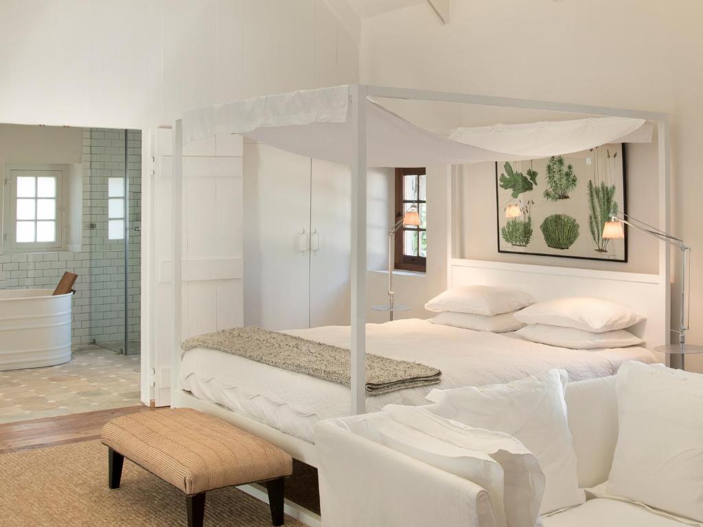 a white bedroom with a canopy bed and a couch at Babylonstoren in Simondium