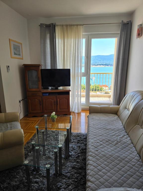 een woonkamer met een bank en een groot raam bij Apartman Vinka in Trogir