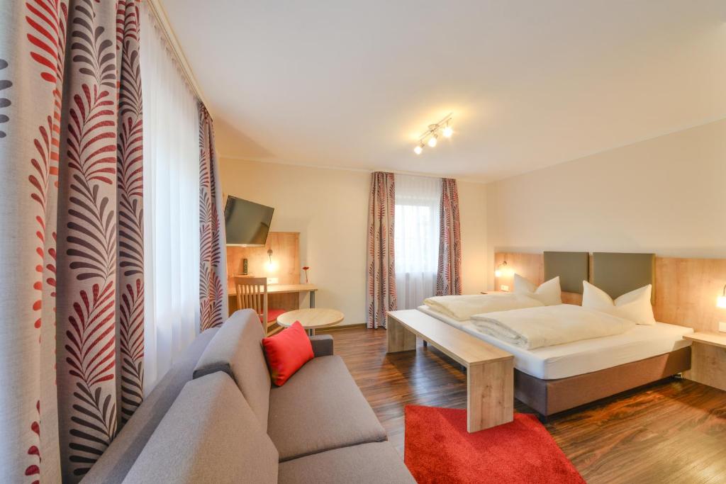 ein Hotelzimmer mit einem Bett und einem Sofa in der Unterkunft Hotel Gasthof Hainzinger in Einsbach