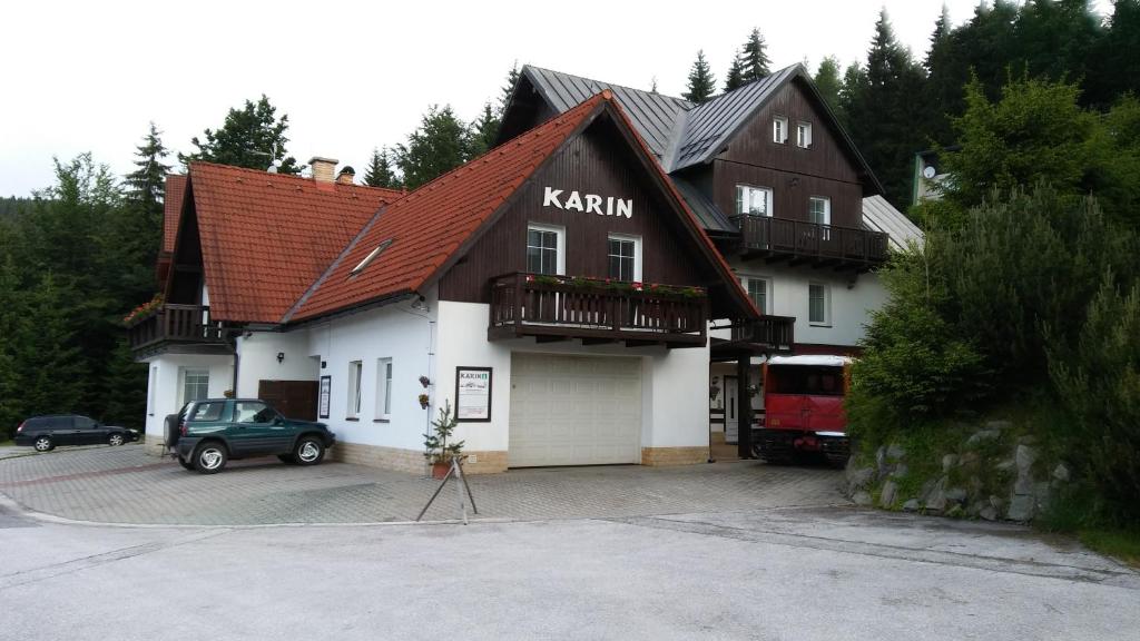 a house with a car parked in a parking lot at Pension Karin in Špindlerův Mlýn