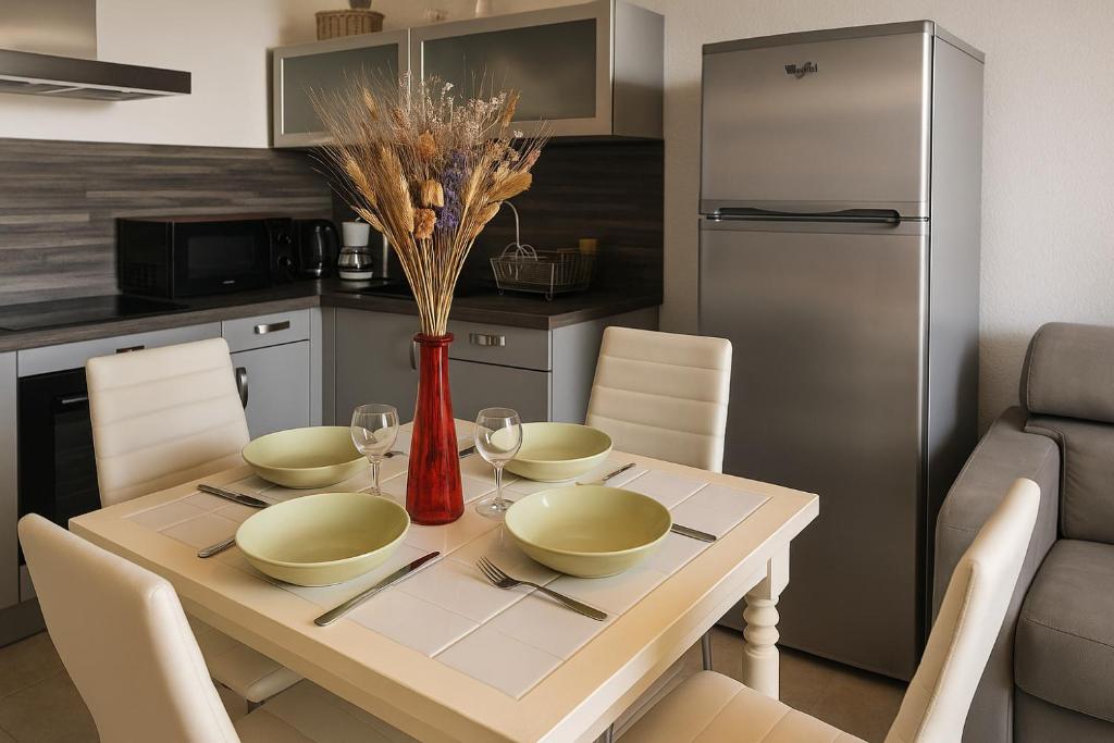 una cucina con tavolo con sedie e frigorifero di Spacieux appartement tout confort proche plage et centre ville Wifi Animaux bienvenus a Saintes-Maries-de-la-Mer