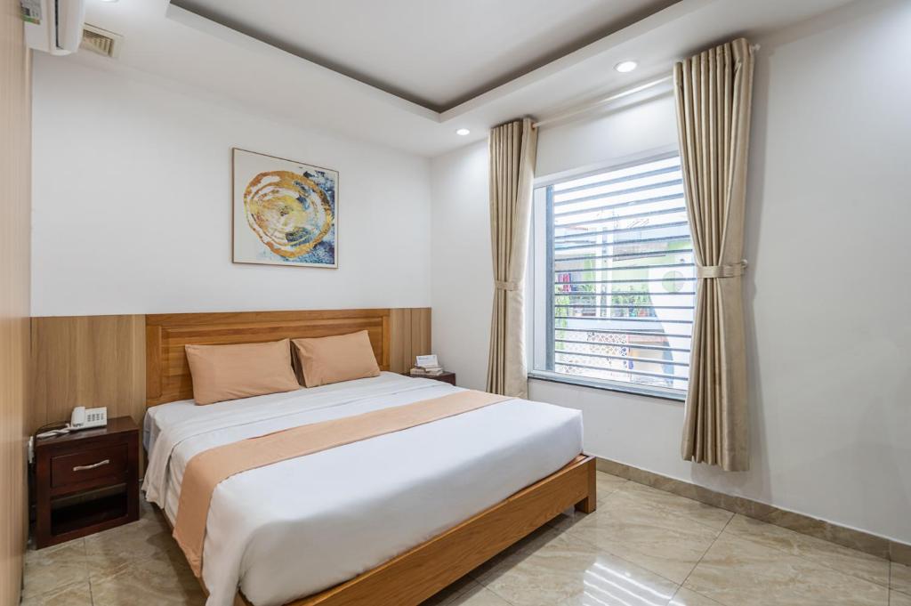a bedroom with a large bed and a window at Cozrum - New Sun Hotel in Ho Chi Minh City