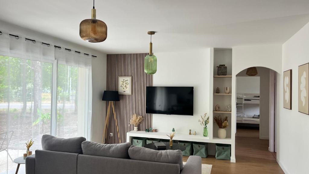 un salon avec un canapé et une télévision dans l'établissement Villa Oyat entre foret et océan, à Grayan-et-lʼHôpital