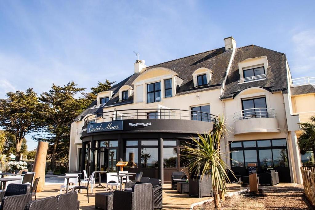 un hotel con tavoli e sedie di fronte a un edificio di Hotel Castel Moor a Le Croisic