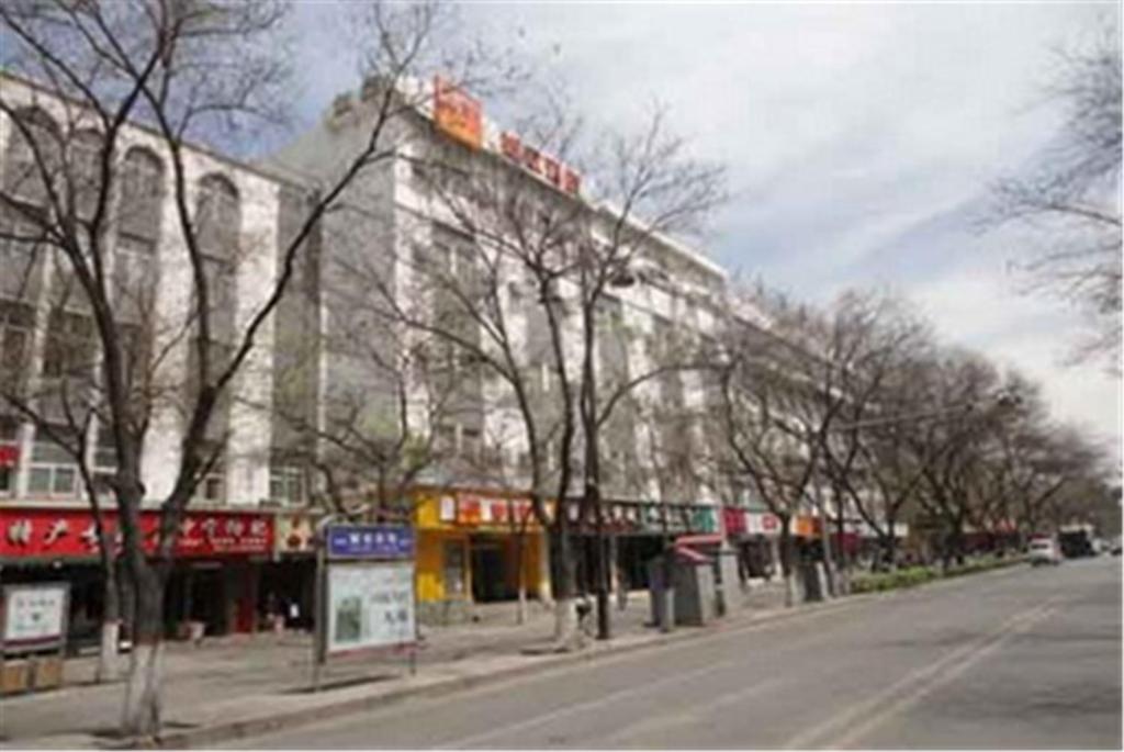 a building on the side of a street with trees at Home Inn Yinchuan Drum Tower Pedestrain Street in Yinchuan