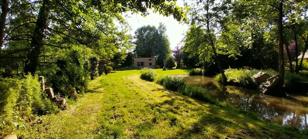 a path through a garden with a house in the background at Le Champ de la Tortue in Saint-Michel-de-Chavaignes