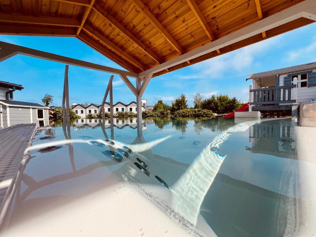 an empty swimming pool with a wooden roof at Biale Domki Paula Rewal - Domki z klimatyzacja, w obiekcie Jacuzzi i darmowe Wifi! in Rewal