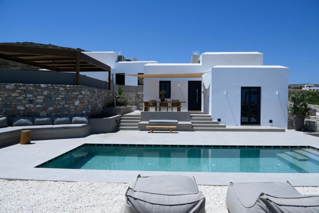 a villa with a swimming pool in front of a house at ANOTERRA VILLAS -Astris in Ambelas