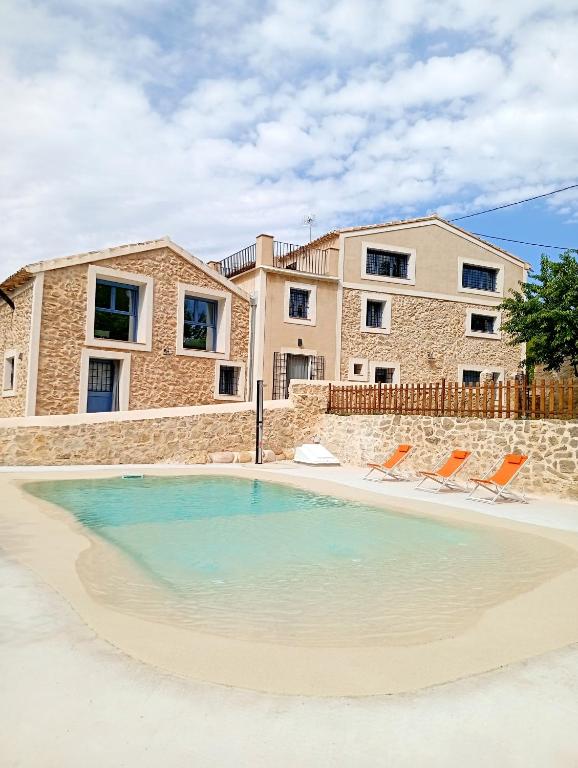 a swimming pool with two chairs and a house at Casa de la Placeta - Casas de Aledo Moratalla in La Risca