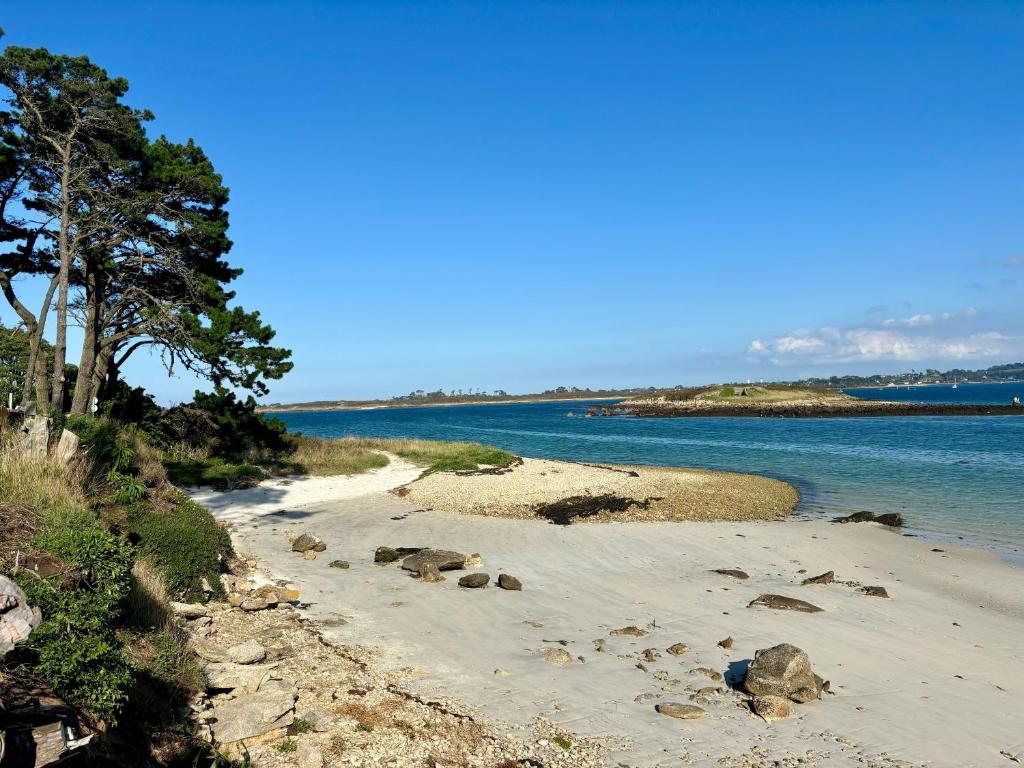 a beach with some rocks and water and trees at Ty Loho - Grande maison à Landéda in Landéda