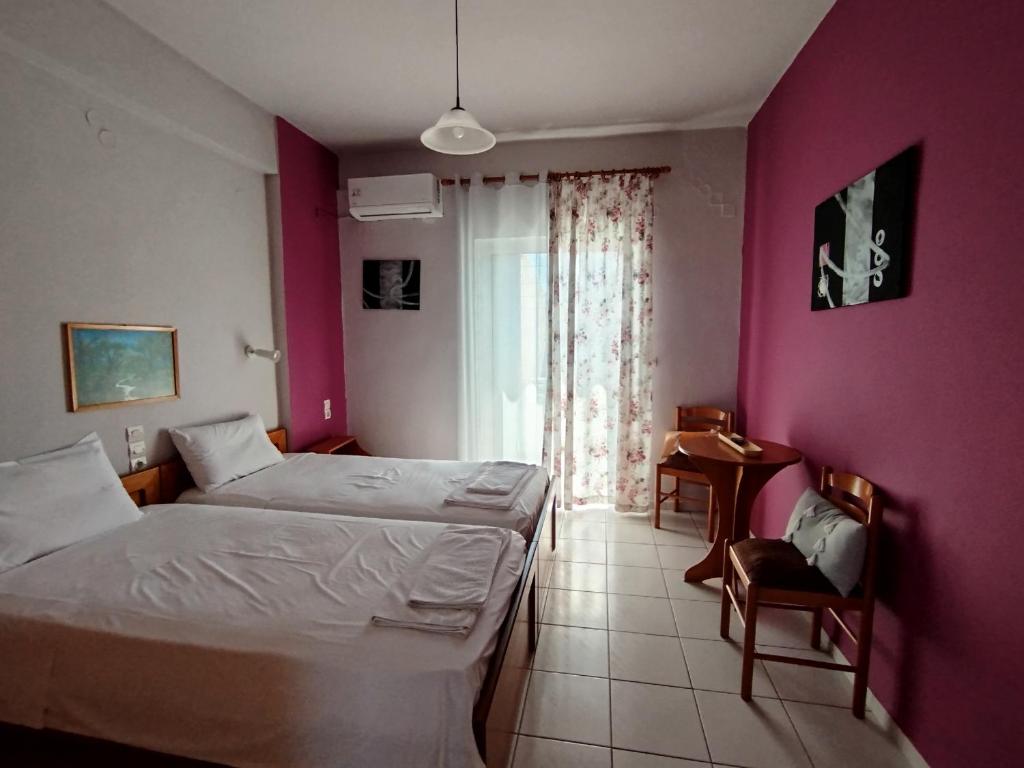 une chambre avec deux lits et un mur rose dans l'établissement Garifalia Studios, à Kalamaki