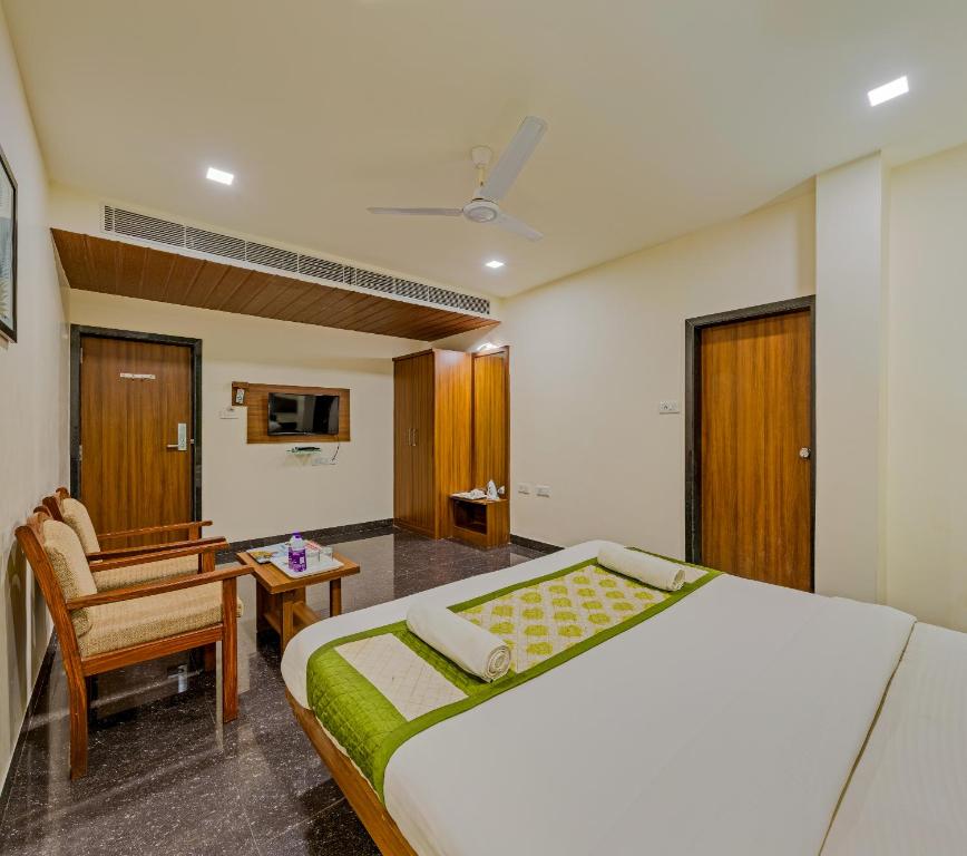 a bedroom with a bed and a desk and a chair at Hotel Vishram Vijayapura Part Of Shubhashree Group in Bijāpur