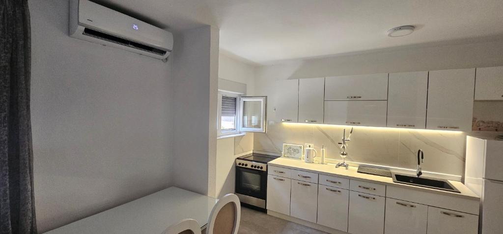 a kitchen with white cabinets and a sink and a stove at Olive Roots Yard House in Trebinje