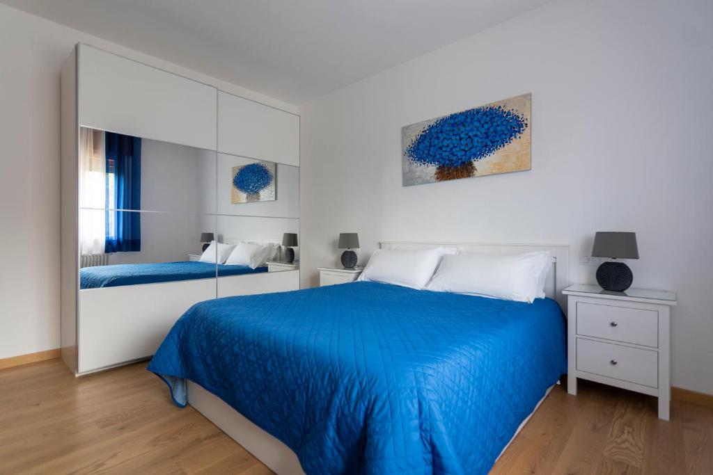 een witte slaapkamer met een blauw bed en een spiegel bij Ca dei Giari in Valdobbiadene