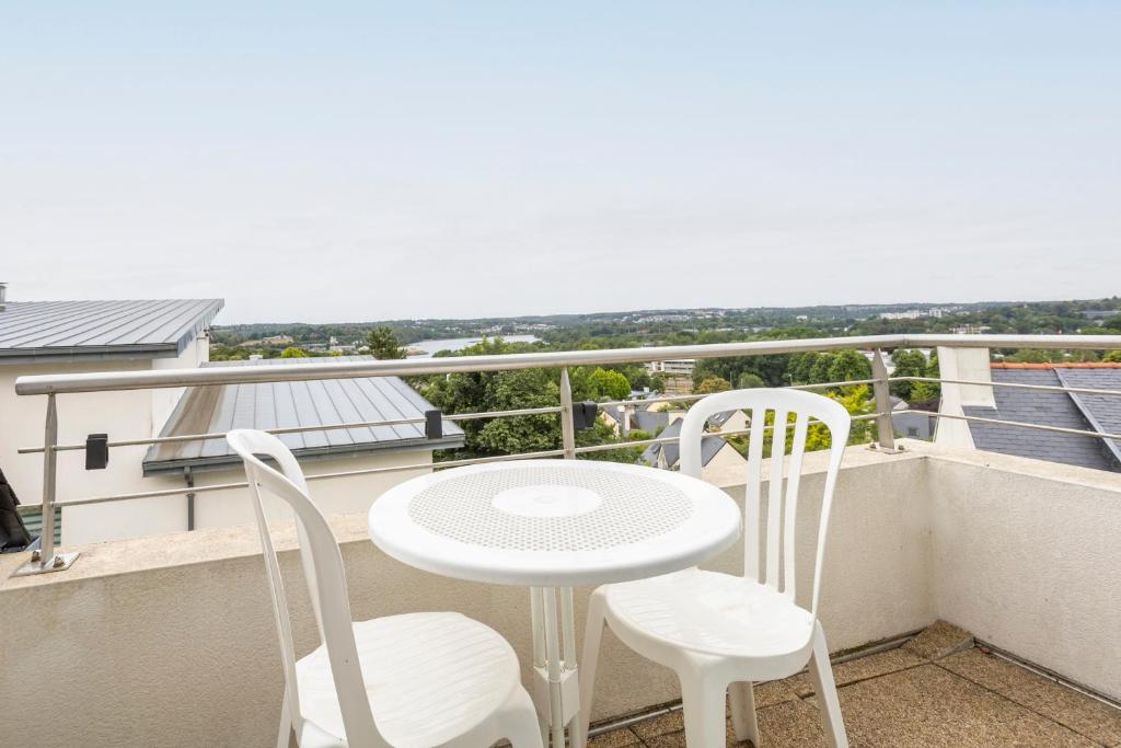une table blanche et des chaises sur un balcon avec vue dans l'établissement Maison de vacances proche de tout, à Quimper