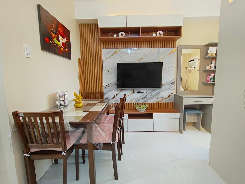 Un comedor con mesa y sillas y un televisor. en Rhiangelo Condo Suite in Cebu City, en Cebú