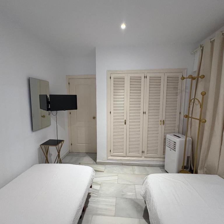 a white room with two beds and a television at Marbella urbanización privada in Marbella