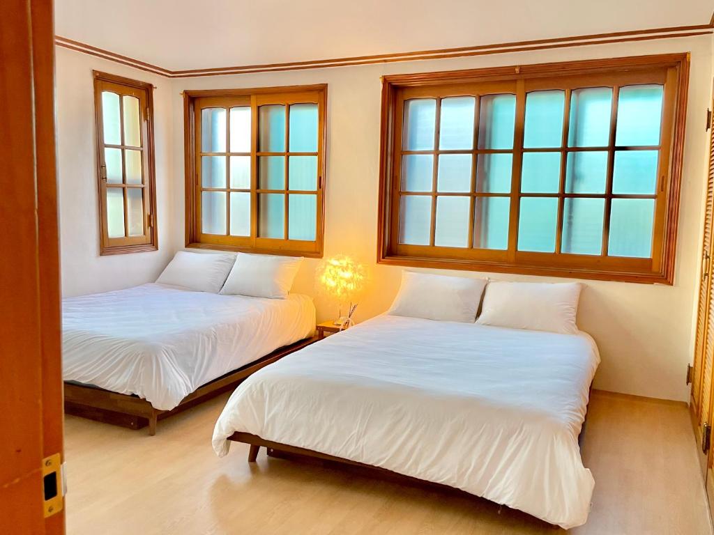 two beds in a room with two windows at Gangneung Sia Stay in Gangneung