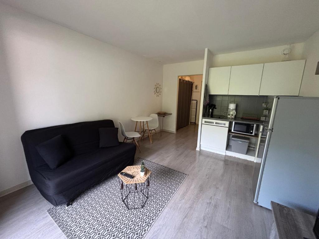 un salon avec un canapé noir et une cuisine dans l'établissement Appartement Les Aigues Marine, aux Lecques