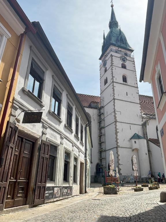 a building with a clock tower on a street at Udírna Penzion and Restaurant in Jindrichuv Hradec