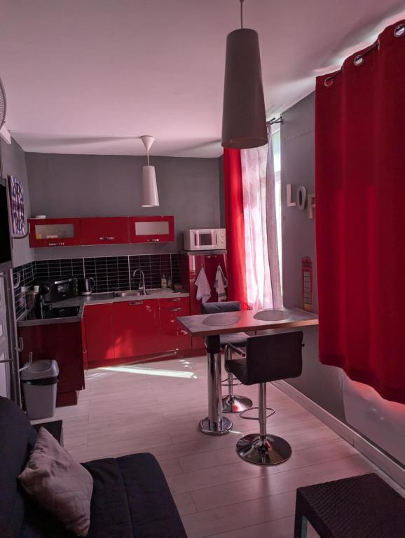 - une cuisine avec des placards rouges et une table dans l'établissement Studio Saint Pierre, à Ault