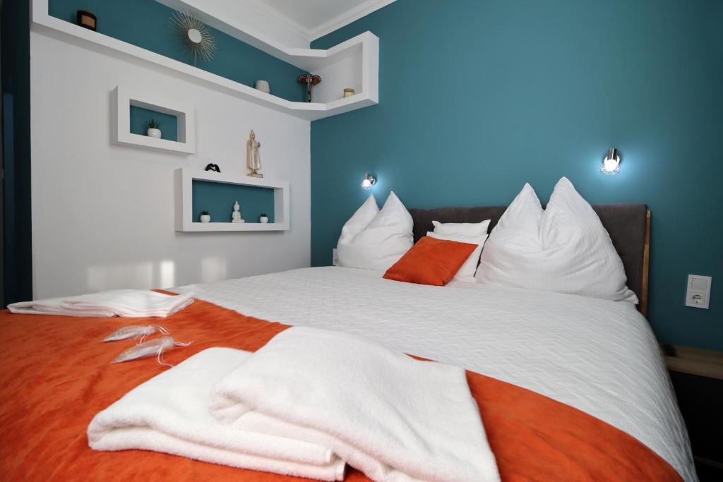 a bedroom with a bed with white sheets and orange pillows at Kilian Suite in Miskolc