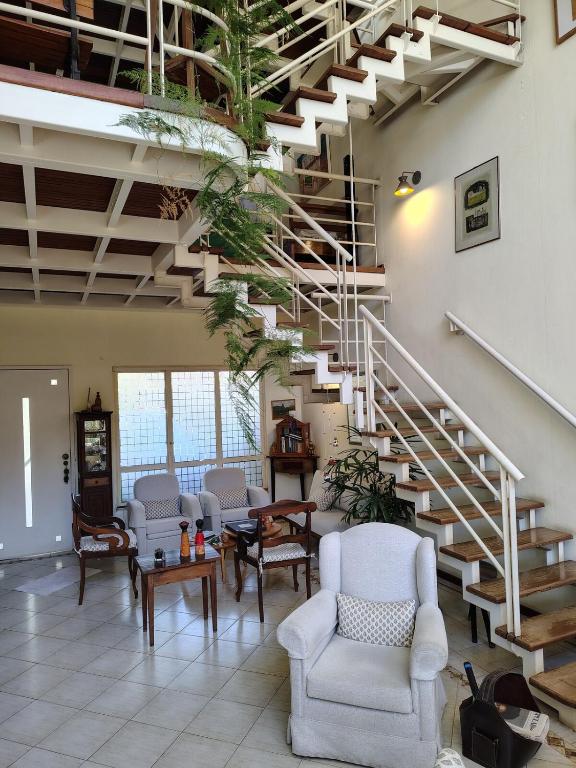 a living room with chairs and a staircase at Casa em Condominio Central in Campinas