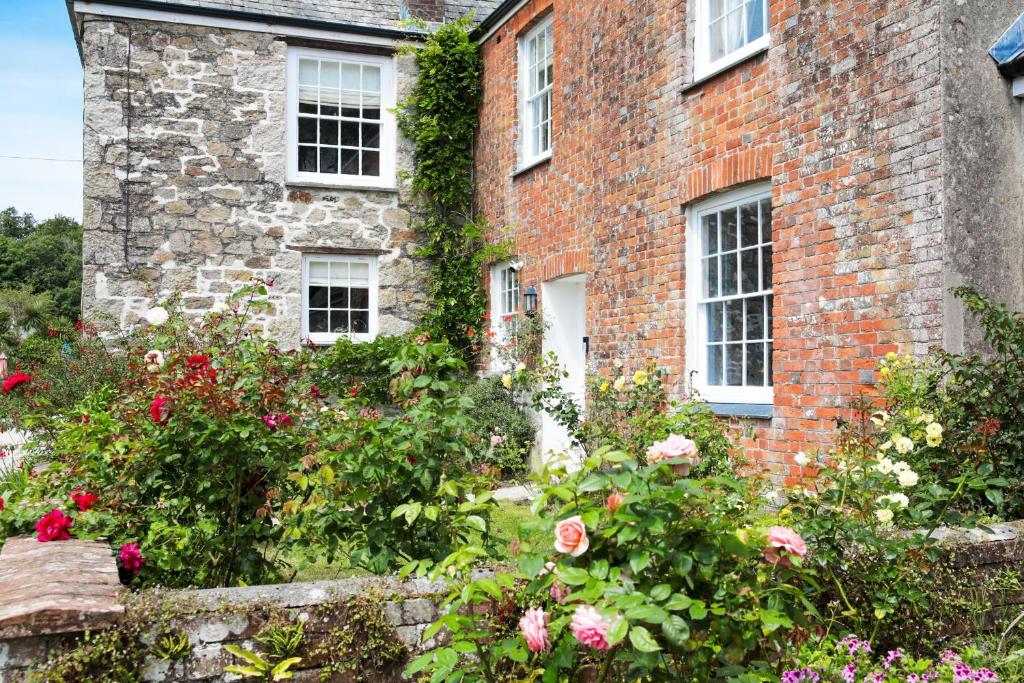 a brick house with flowers in front of it at Polmear Farm Manor House in Charlestown
