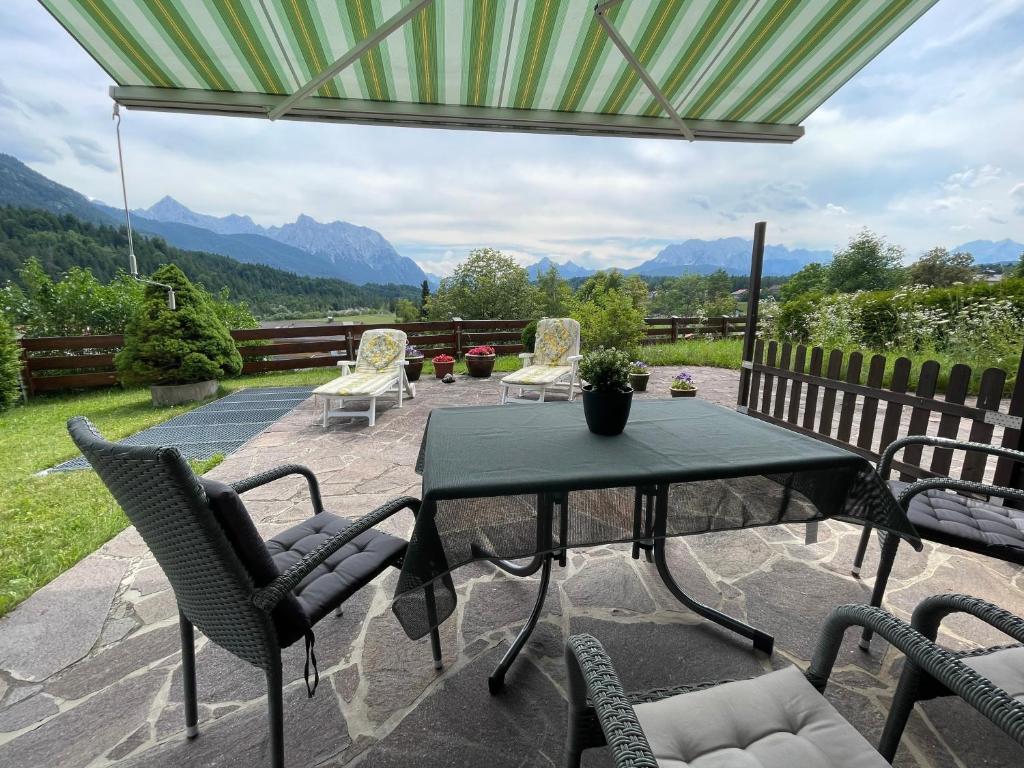 a patio with a table and chairs with mountains in the background at Alpenjuwel in Krün